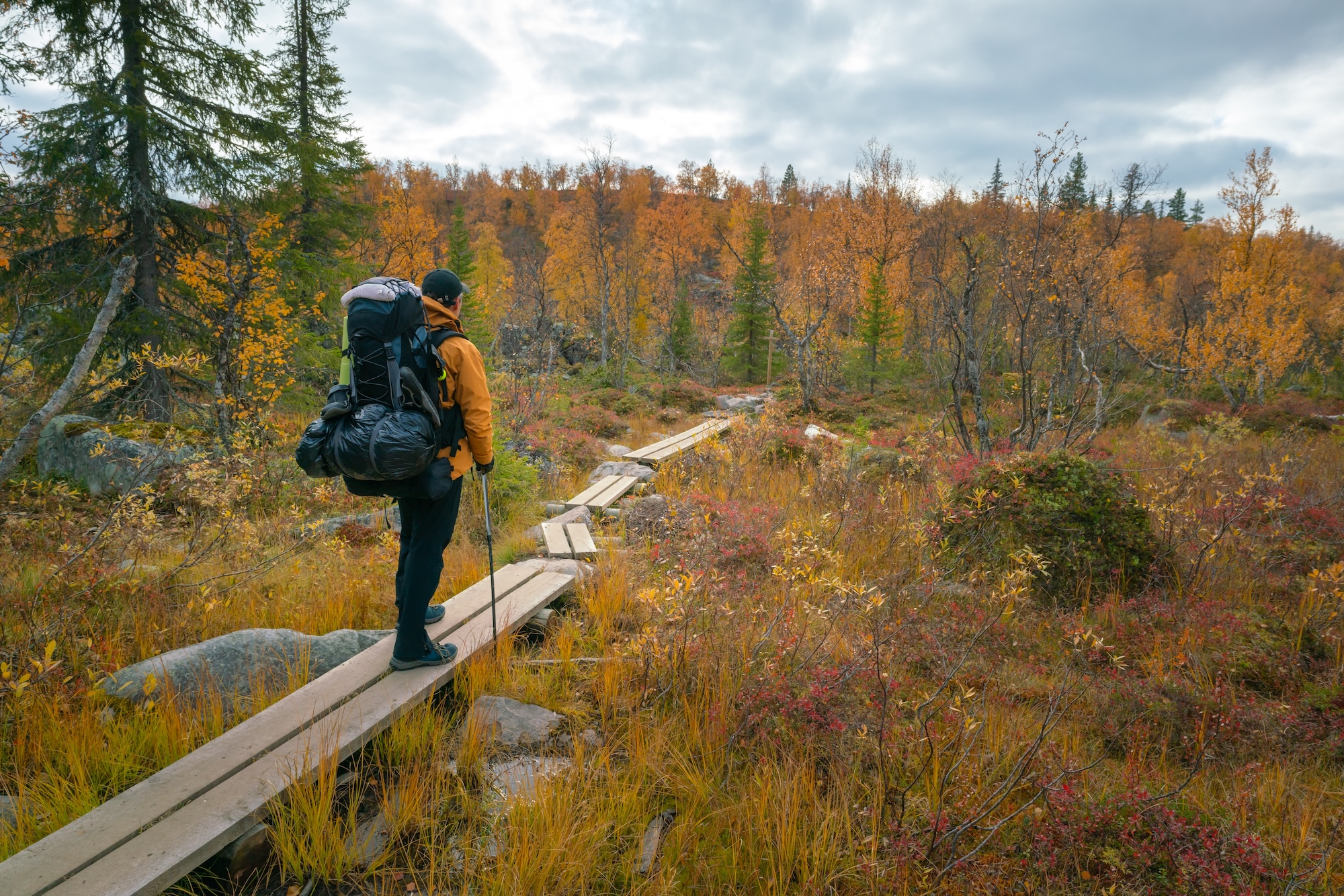 malehikerinyellowjacketwithheavybackpackandhiking