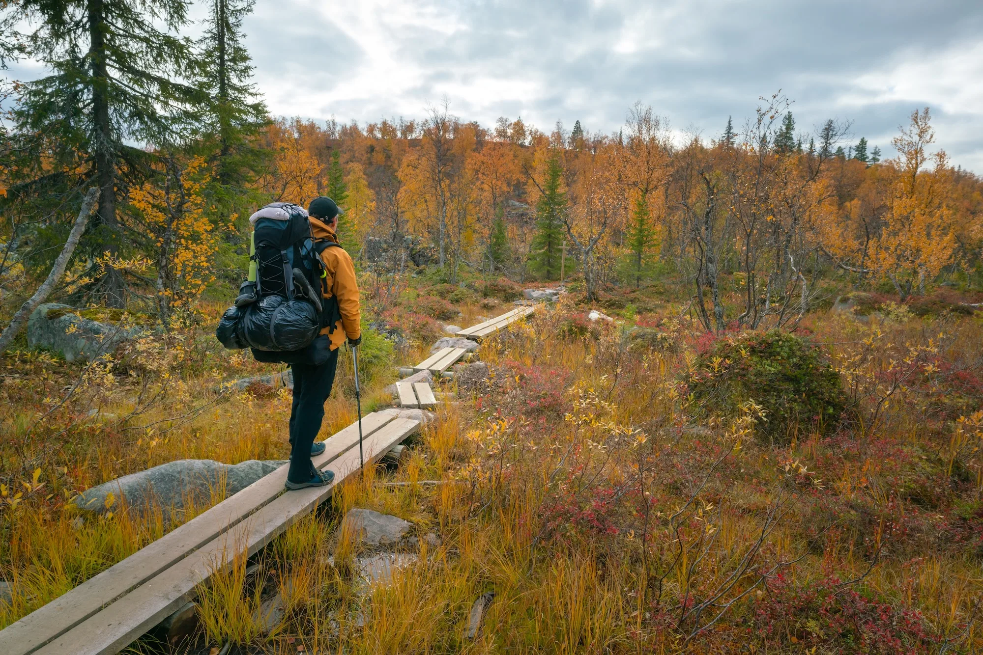 malehikerinyellowjacketwithheavybackpackandhiking